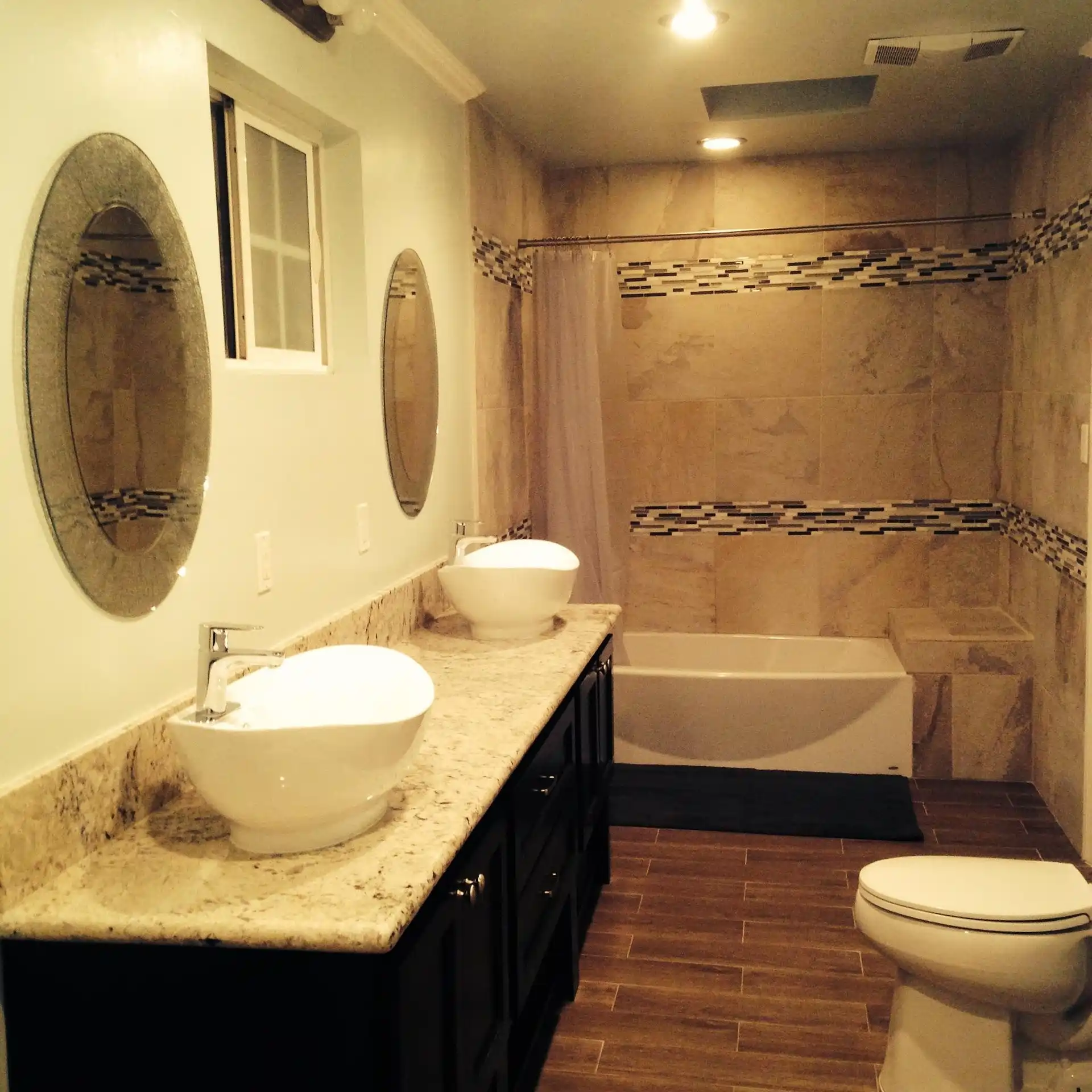 Travertine bathroom wall tiles with decorative mosaic border strip and double vessel sinks